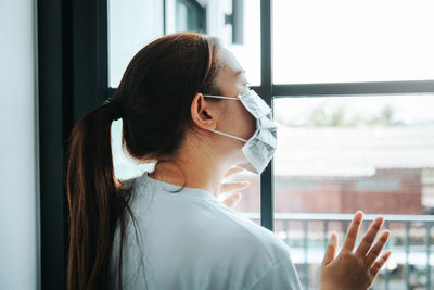 Portrait of young woman looking through window