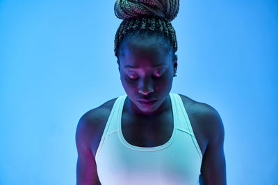 Portrait of young woman against blue background