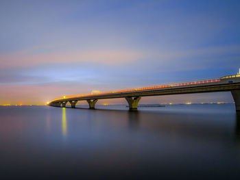 Bridge over sea against sky during sunset