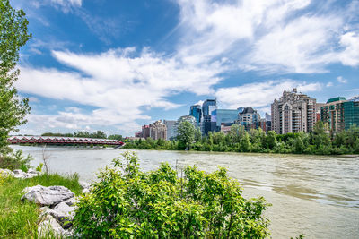 Scenic view of river by buildings against sky