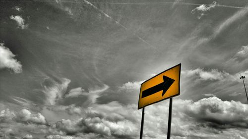 Low angle view of road sign against cloudy sky