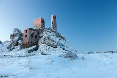 Low angle view of historic building against clear blue sky during winter