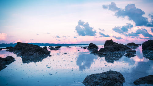 Rocks on shore against sky during sunset