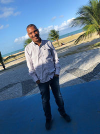 Full length portrait of young man standing against sky