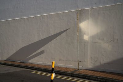 Shadow of traffic sign on road against wall