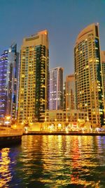 Reflection of illuminated buildings in city at dusk