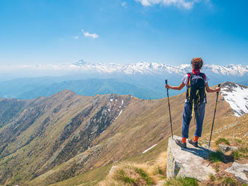 Rear view of man standing on mountain against sky