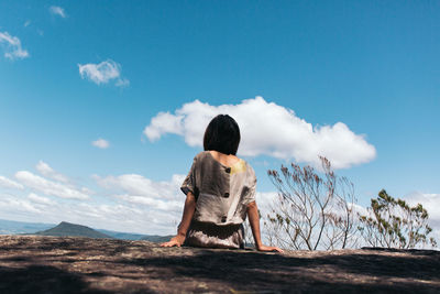 Rear view of man sitting on rock