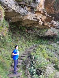 Full length of woman standing on rock in forest