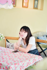 Portrait of young woman sitting on bed at home