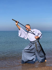 Man gripping samurai sword on beach