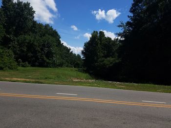 Road by trees against sky