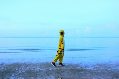 Side view of person in tiger costume walking at beach