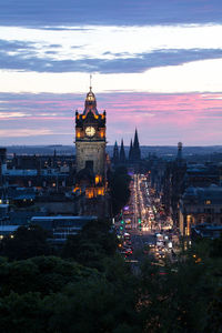 Illuminated buildings in city at sunset