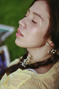 Close-up of woman with eyes closed wearing flowers on hair