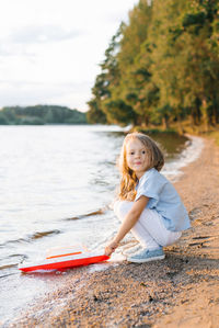 A girl launches a boat into the lake