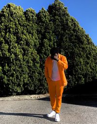 Young man standing on road against trees