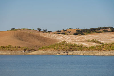 Desert like hill landscape with reflection on the water on a dam lake reservoir in terena, portugal