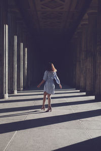 Rear view of woman standing at colonnade