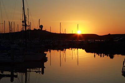 Boats moored at harbor during sunset