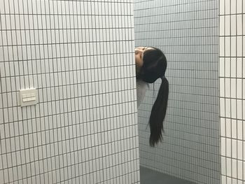 Cropped image of woman by wall in bathroom