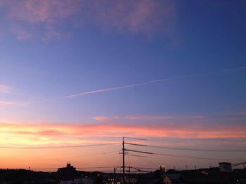 Silhouette electricity pylons against sky during sunset