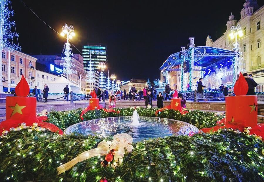 architecture, building exterior, built structure, water, illuminated, city, night, multi colored, incidental people, travel destinations, tree, sky, fountain, reflection, outdoors, decoration, celebration, tourism, city life, famous place