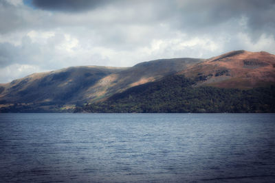 Scenic view of lake by mountains against sky