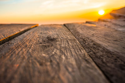 Surface level of wooden table against sky during sunset