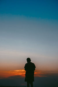 Rear view of silhouette man standing against sky during sunset