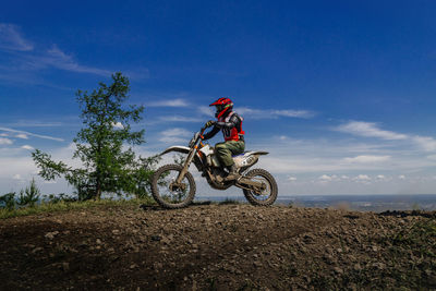 Man riding bicycle on field against sky