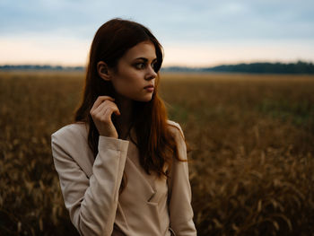 Young woman standing on field against sky