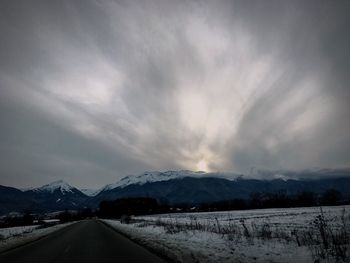 Road passing through landscape against cloudy sky