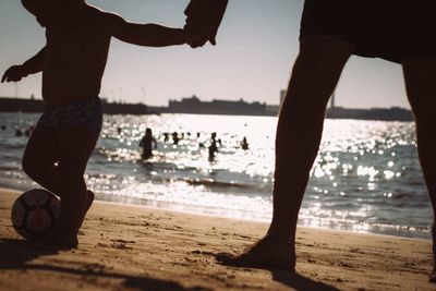 Silhouette people at beach against sky