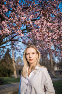 Portrait of young woman standing against trees