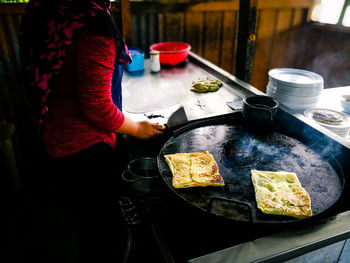 Midsection of woman preparing roti canai food