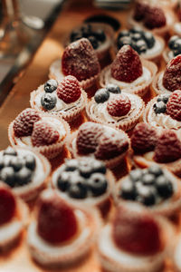 Sweet tiny cakes with fluffy cream and red berries