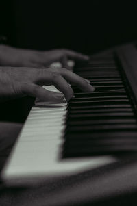 Cropped hands playing piano in darkroom