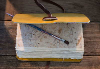 High angle view of paintbrush on book at wooden table