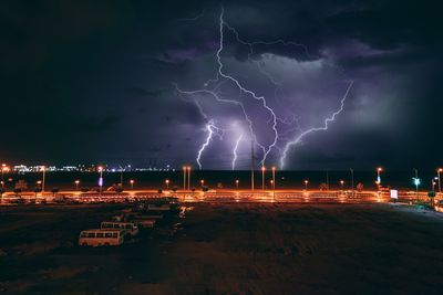 Lightning over illuminated city against dramatic sky at night