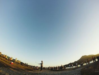 Surface level of people walking on road against clear sky