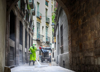 Man cleaning alley amidst building