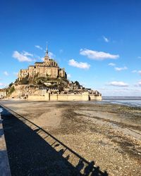 View of building by sea against blue sky