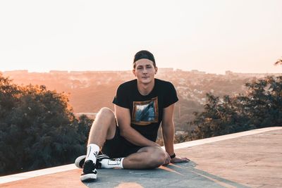 Portrait of young man sitting against clear sky