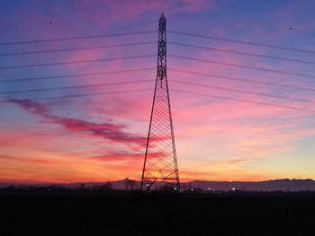 Low angle view of silhouette electricity pylon against dramatic sky