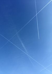 Low angle view of vapor trails in blue sky