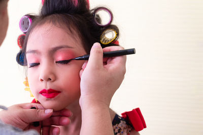 Cropped hand of woman applying make-up to girl