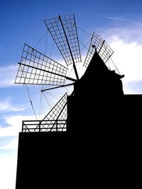 Low angle view of silhouette crane against sky