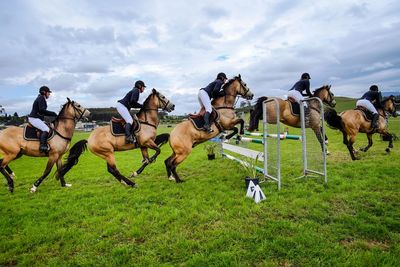 People horse racing on field