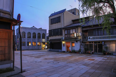 Street by buildings against sky at dusk